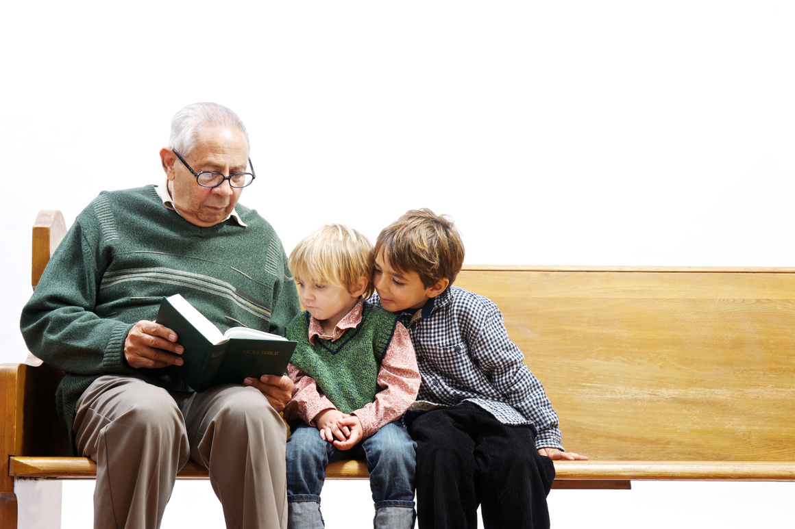 Elderly man reading the Bible to young children